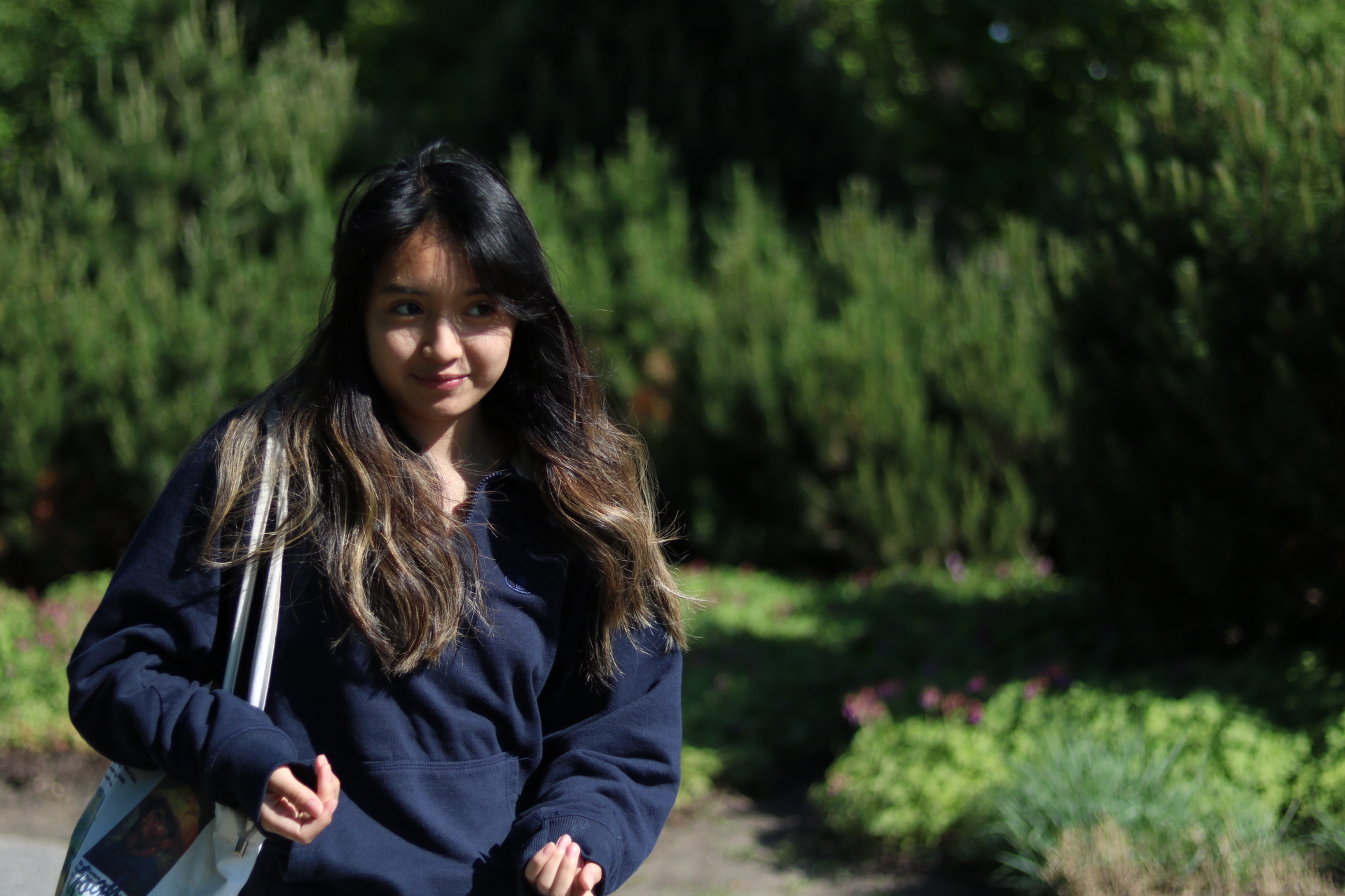 A candid photo of a girl posed in a forest, holding her camera