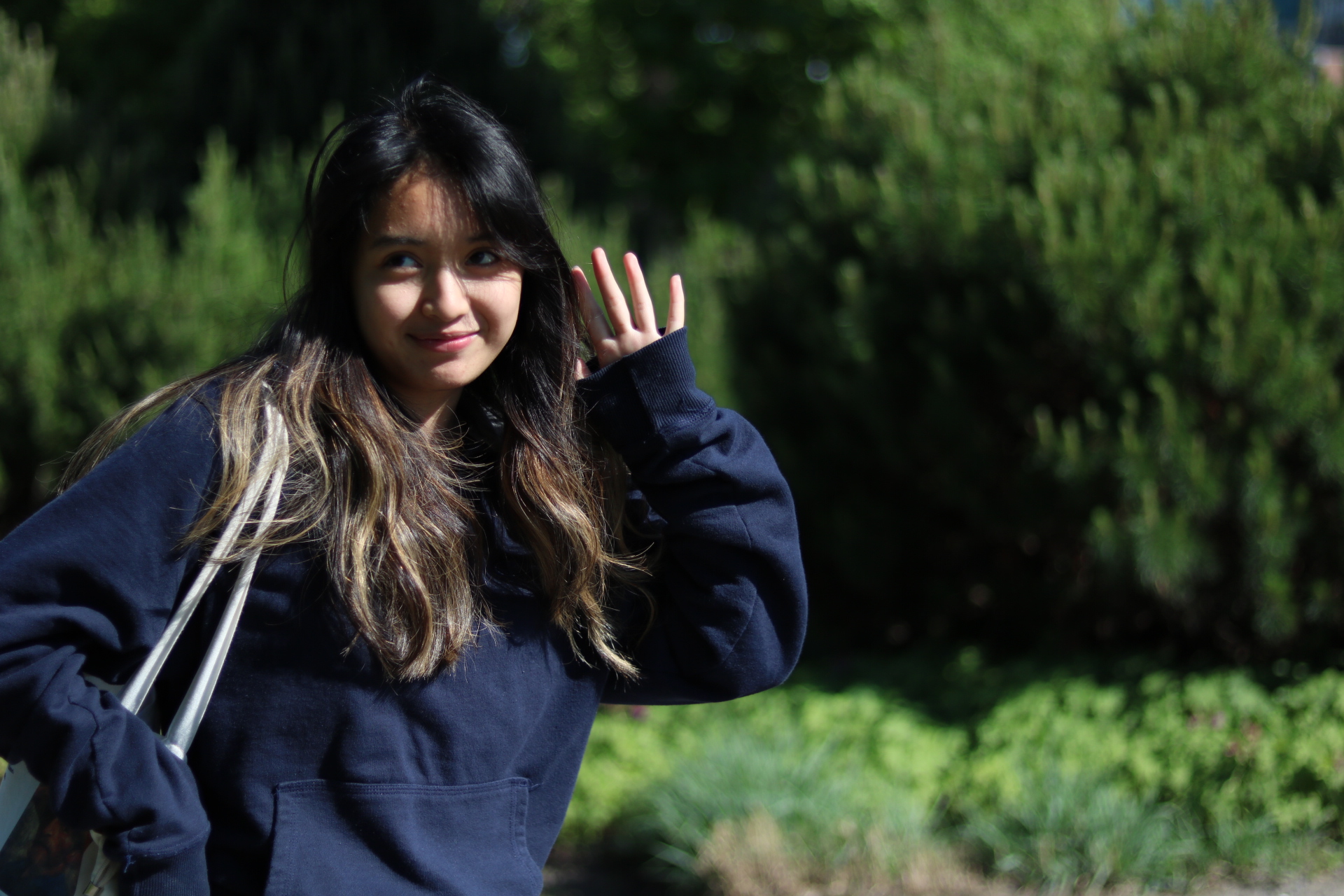 A candid photo of a girl posed in a forest, holding her camera