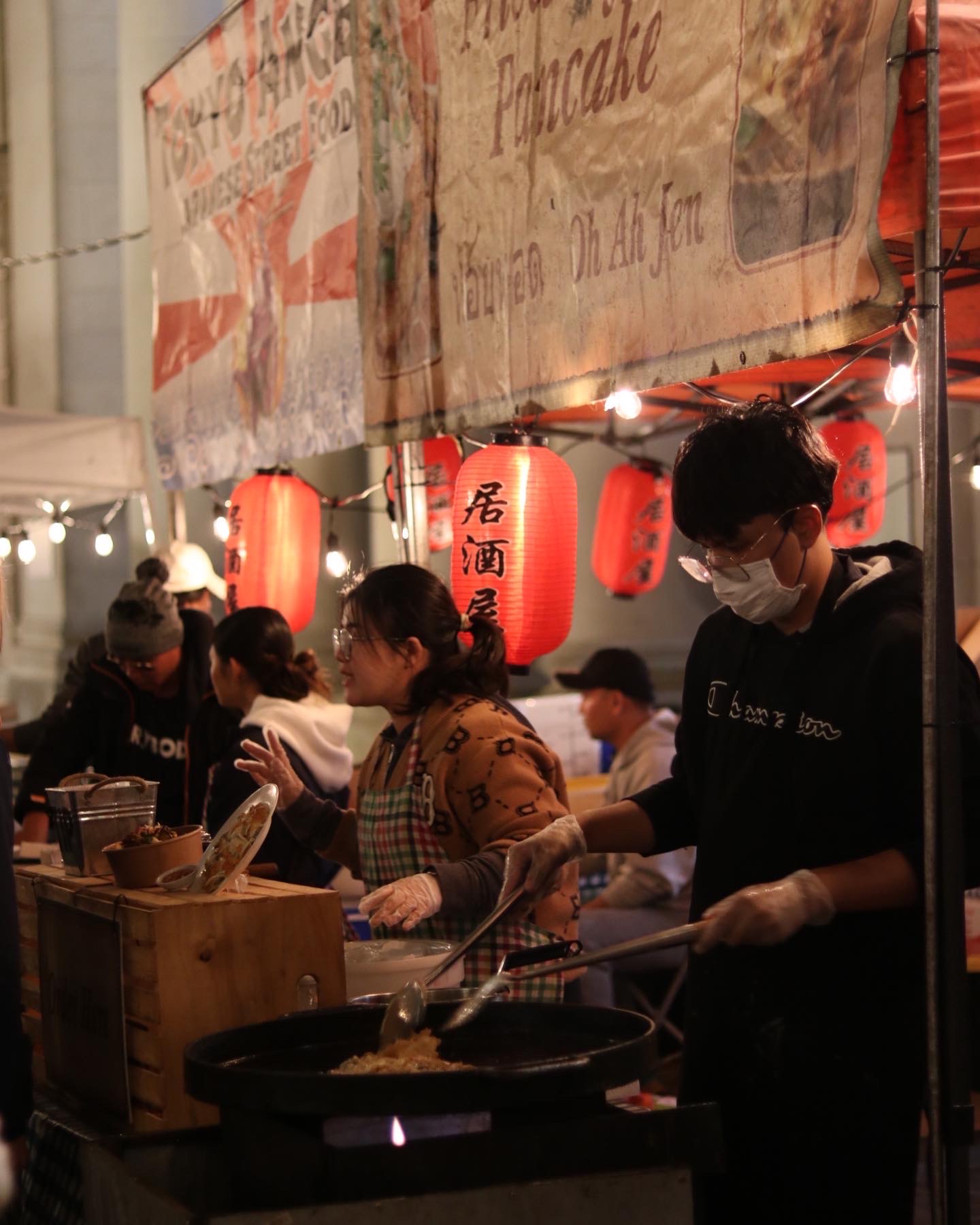 a woman knitting a pair of socks in her kiosk at a christmas night market