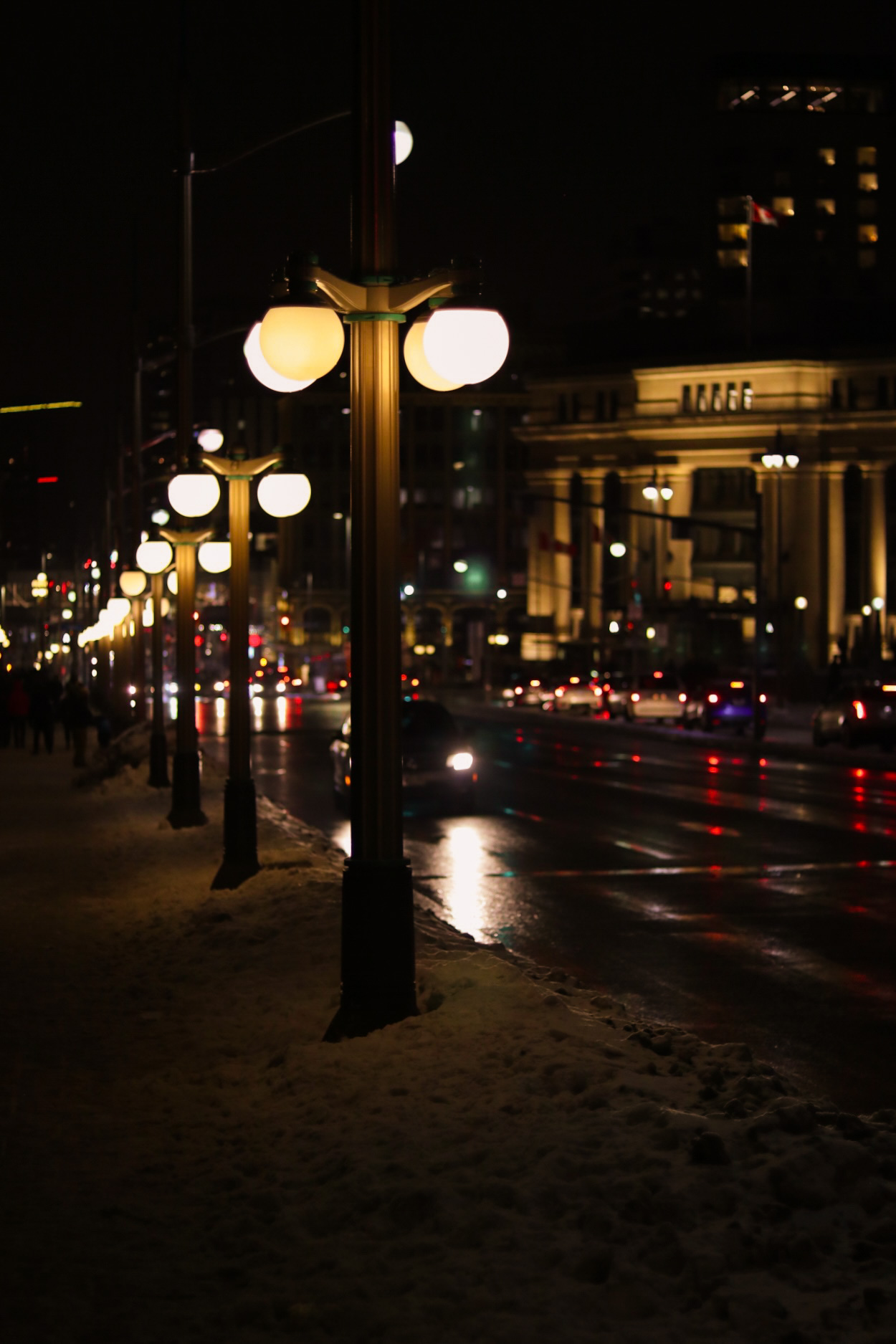 A series of lamp-posts lit at night along a street